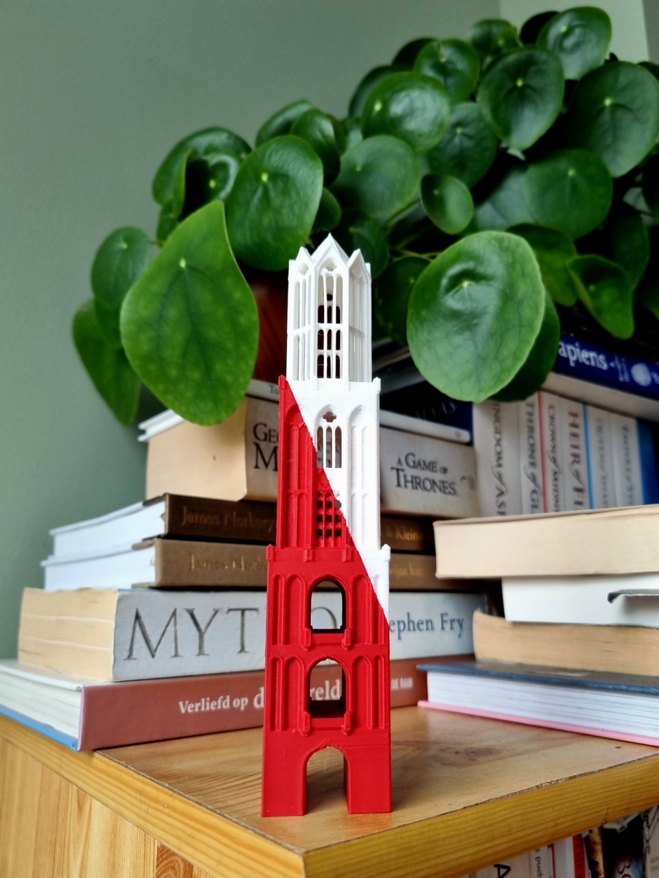 De Premium Utrecht Edition van de Domtoren op een boekenplank, naast een plant: onderin rood, bovenin wit, met een diagonale scheiding zoals de Utrechtse vlag
